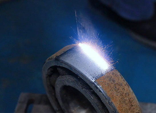 Funken sprühen von einem Laserreinigungsprozess auf einer Radlageroberfläche.
